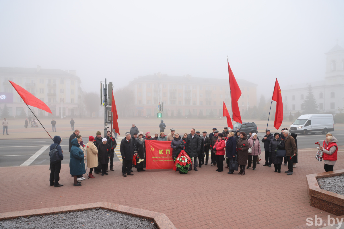 Люди с красными флагами на митинге в Бресте 7 ноября 2024 года, участники держат флаг КП и цветы/