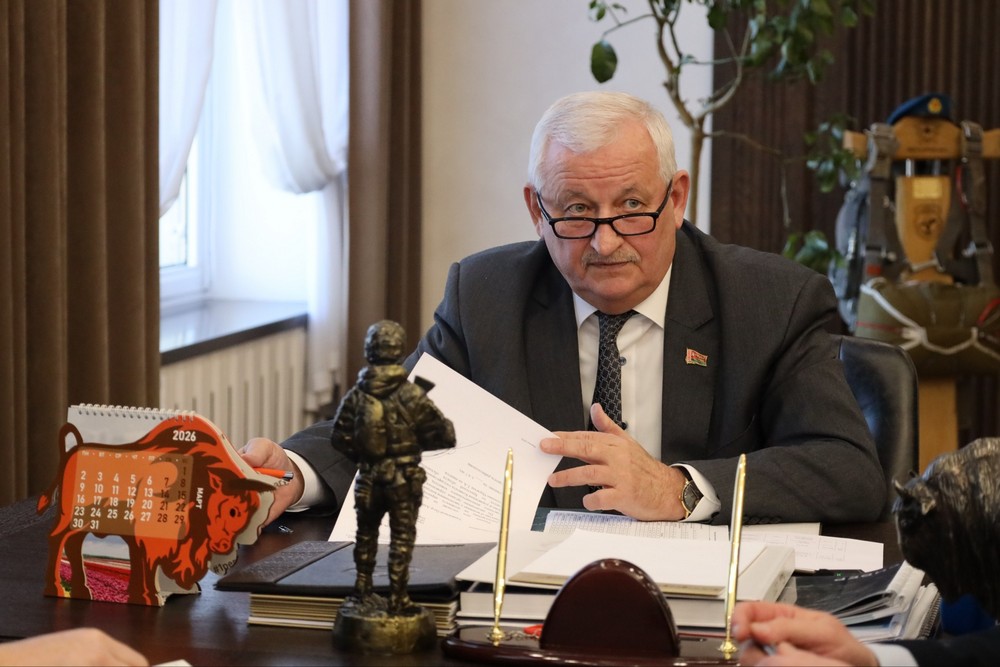 Петр Пархомчик в своем кабинете 2 февраля 2026 года. На столе есть скульптура военнослужащего. На заднем фоне парашют и голубой берет